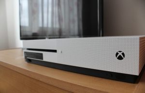 The side view of an xbox one an Tv in background
