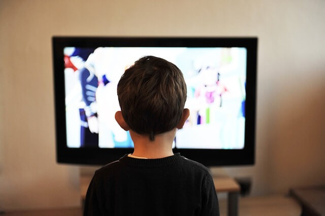 child standing in front of a TV screen