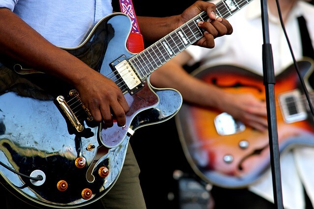 close up of two people playing guitars
