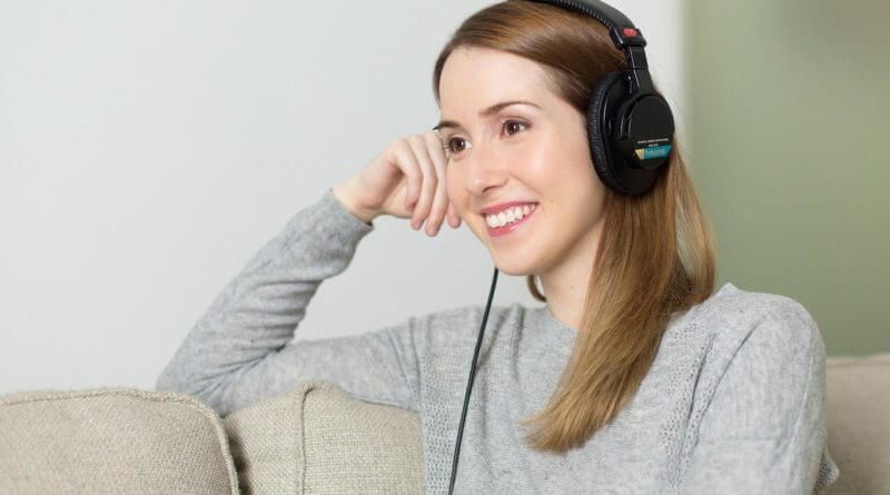 woman sitting on couch wearing headphones