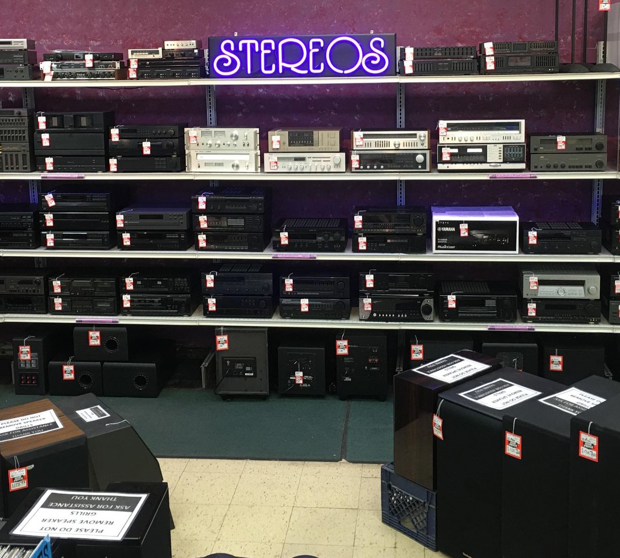 Stereos for sale. Neon Purple sign above stereo section.